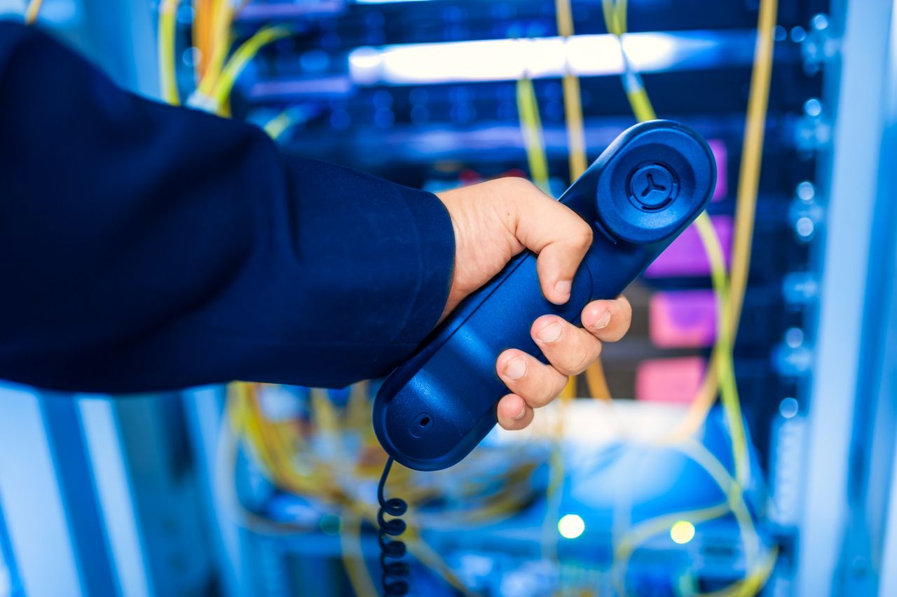 Crafting Captivating Headlines: Your awesome post title goes here Close-up of a hand holding a telephone receiver in a server room emphasizing technology.